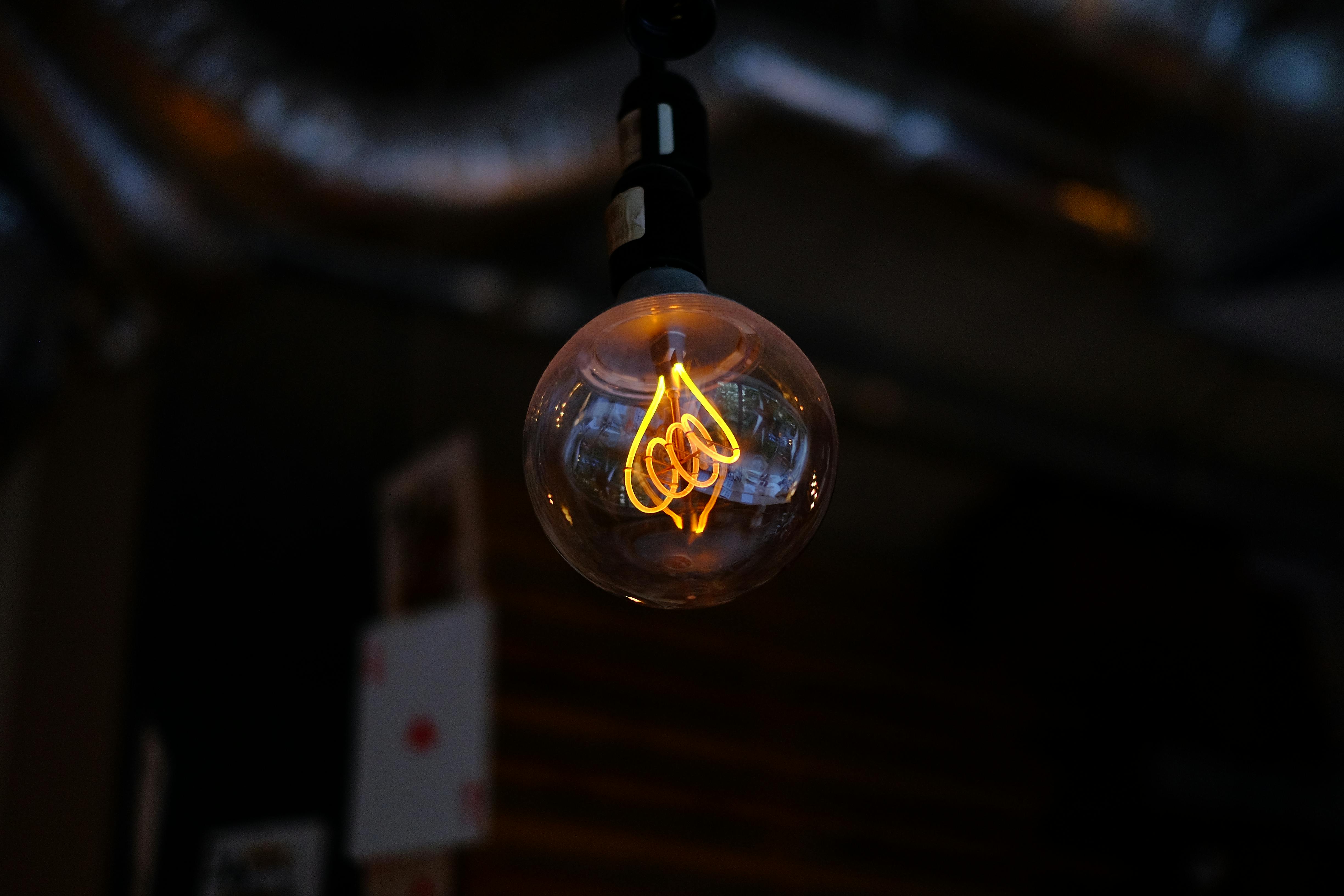 A glowing vintage Edison bulb hanging in a dimly lit indoor space, casting a warm ambiance.